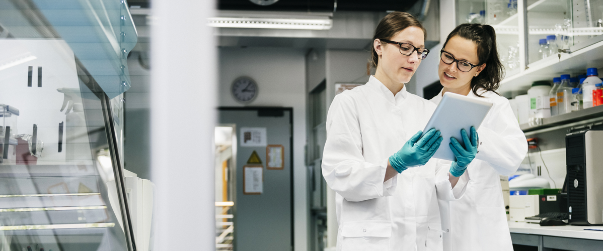 Deux femmes scientifiques dans un laboratoire, discutant de données médicales.