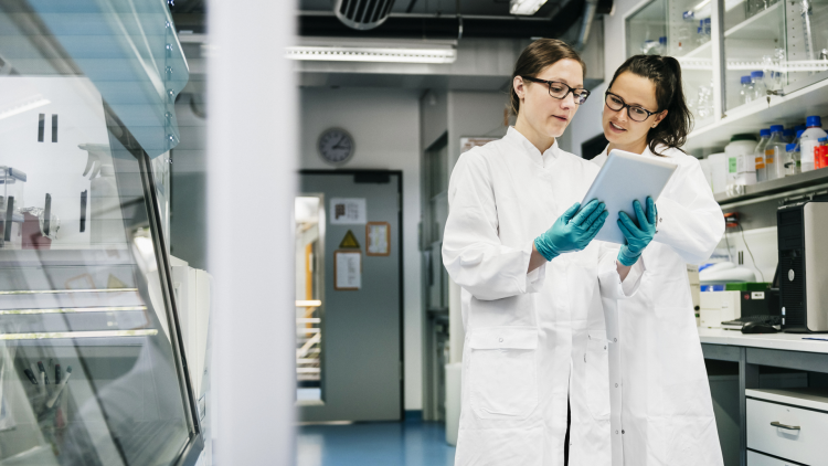 Deux femmes scientifiques dans un laboratoire, discutant de données médicales.