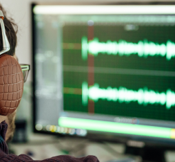Un homme équipé d’un casque analyse le son d’une voix sur son ordinateur.
