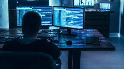 A man inspecting data on several bluish screens