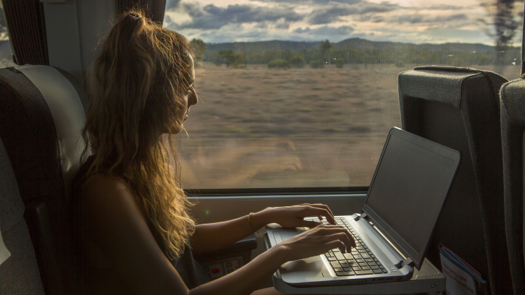 Une jeune femme regarde un vidéo en live sur son ordinateur dans le train