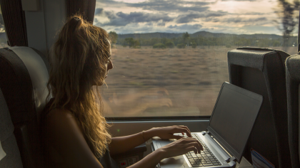 Une jeune femme regarde un vidéo en live sur son ordinateur dans le train