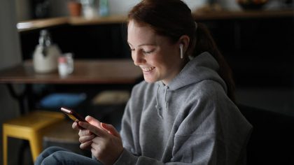 A woman smiles at her smartphone