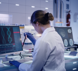 A screen features DNA in front of a lab worker