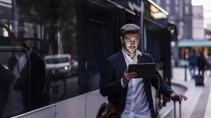 A man with a tablet next to a bus