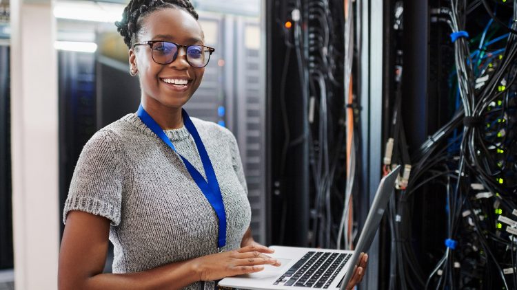 Une développeuse avec son ordinateur devant une armoire informatique