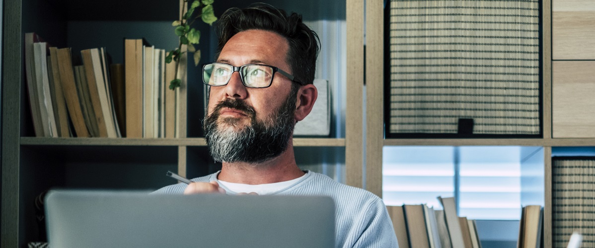 Getty Images - Thoughtful businessman with laptop sitting at desk in home office