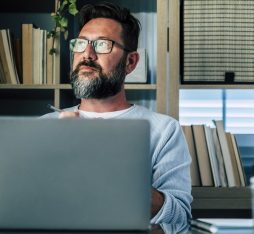 Getty Images - Thoughtful businessman with laptop sitting at desk in home office