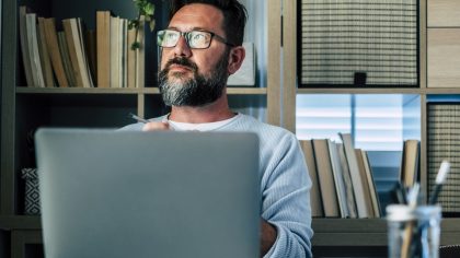 Getty Images - Thoughtful businessman with laptop sitting at desk in home office