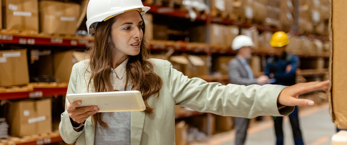 Getty Images - With a tablet in hand, a female warehouse owner walks through her busy warehouse. Dressed in smart business attire, reviewing logistics or inventory data. The spacious warehouse with neatly stocked shelves provides a clear view of the scale of the operation, emphasizing the owners hands-on approach to managing her business.