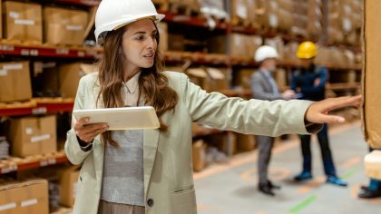 Getty Images - With a tablet in hand, a female warehouse owner walks through her busy warehouse. Dressed in smart business attire, reviewing logistics or inventory data. The spacious warehouse with neatly stocked shelves provides a clear view of the scale of the operation, emphasizing the owners hands-on approach to managing her business.