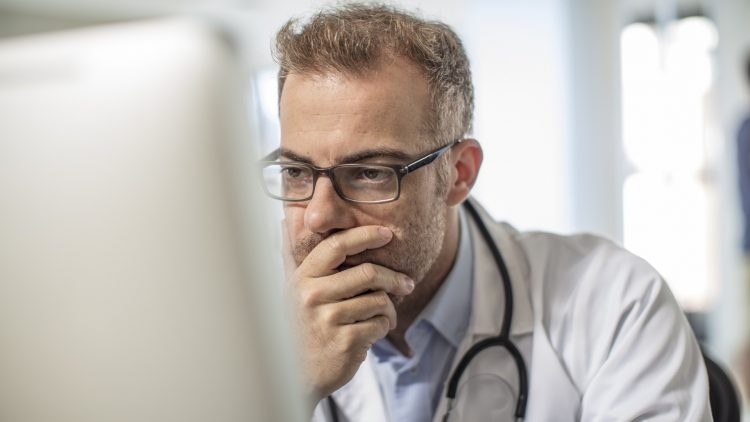 Getty Images - Cape Town, South Africa, Doctor sitting at desk working on computer