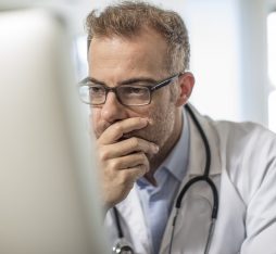 Getty Images - Cape Town, South Africa, Doctor sitting at desk working on computer