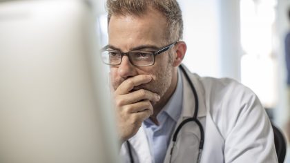 Getty Images - Cape Town, South Africa, Doctor sitting at desk working on computer