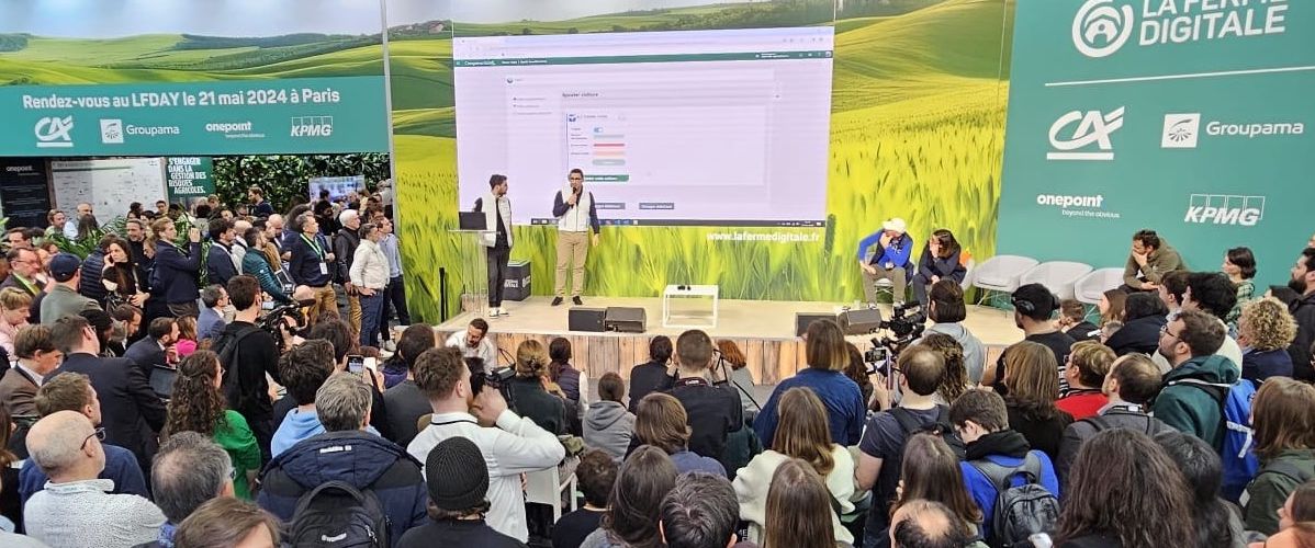 Une foule attentive assiste à une présentation sur scène lors d'un événement