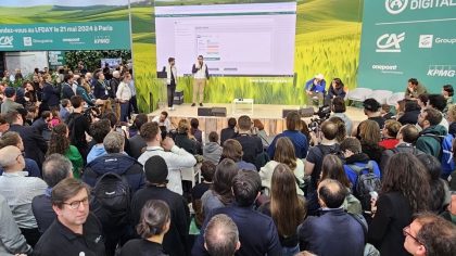 An attentive crowd watches a presentation on stage during an event