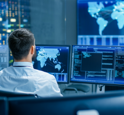 A man at his desk checks datasets on multiple screens