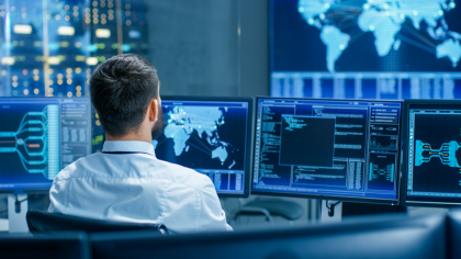 A man at his desk checks datasets on multiple screens
