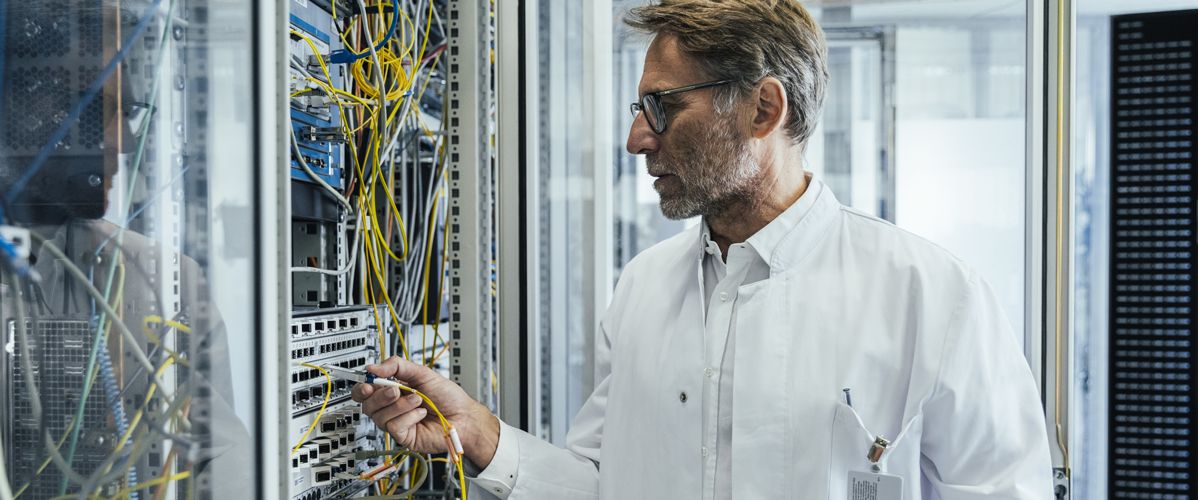 Un homme branche une fibre dans une armoire informatique