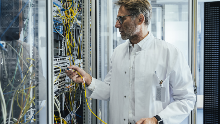 Un homme branche une fibre dans une armoire informatique