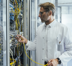 Un homme branche une fibre dans une armoire informatique