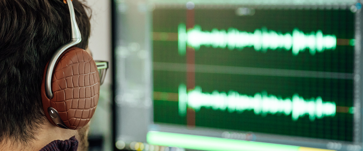 Un homme équipé d’un casque analyse le son d’une voix sur son ordinateur.