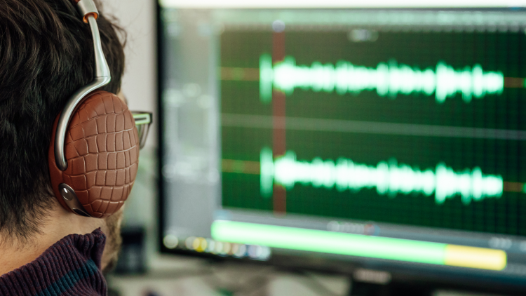 Un homme équipé d’un casque analyse le son d’une voix sur son ordinateur.