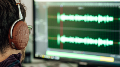 Un homme équipé d’un casque analyse le son d’une voix sur son ordinateur.