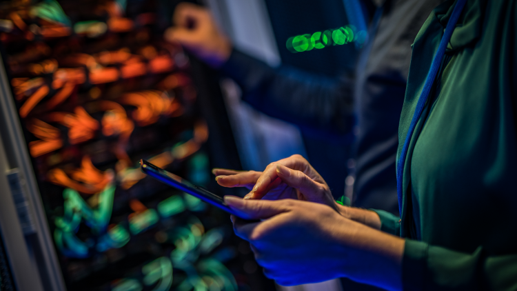 Male and female IT engineers checking servers in server room with help of tablet
