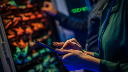 Male and female IT engineers checking servers in server room with help of tablet
