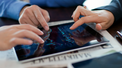 Trois personnes comparent des données sur une tablette.