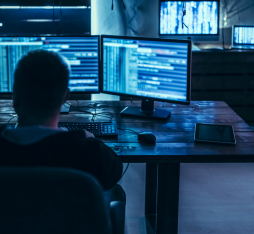 A man inspecting data on several bluish screens