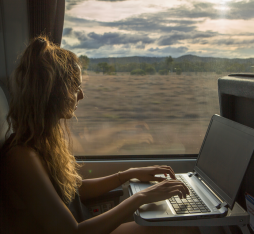 Une jeune femme regarde un vidéo en live sur son ordinateur dans le train