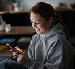 A woman smiles at her smartphone