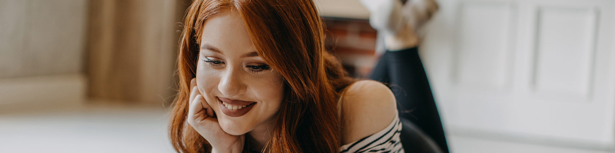 Une femme regarde son écran en souriant