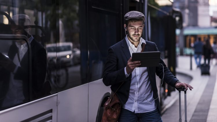 Un homme avec une tablette à côté d'un bus