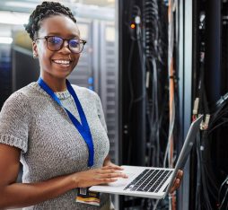 Une développeuse avec son ordinateur devant une armoire informatique
