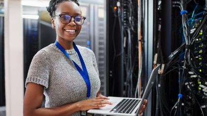 Une développeuse avec son ordinateur devant une armoire informatique