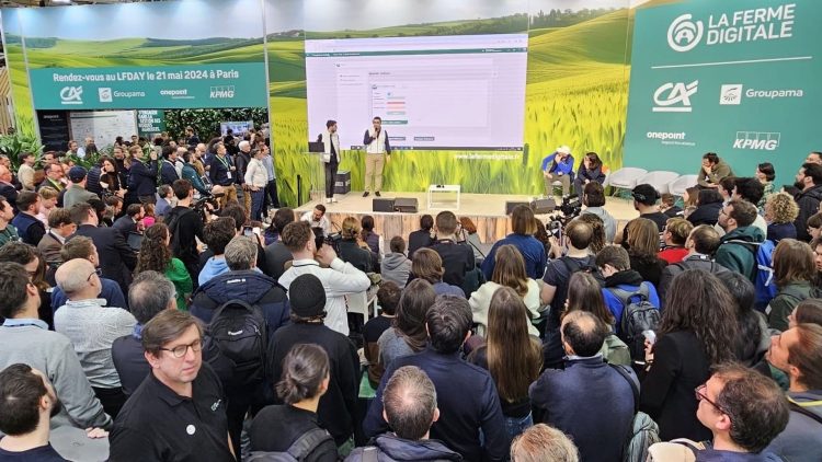 Une foule attentive assiste à une présentation sur scène lors d'un événement