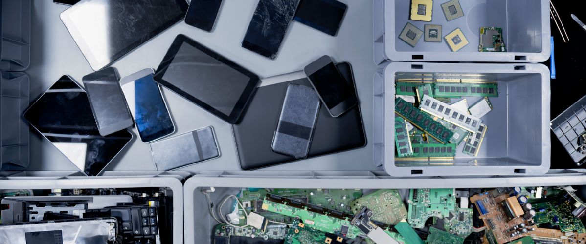 Various electronic devices, such as phones and tablets, along with internal components, are arranged in bins.