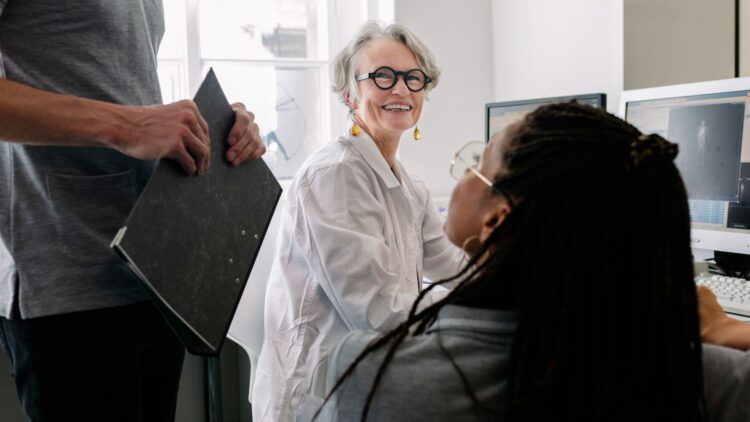 Équipe de recherche travaillant ensemble dans un laboratoire, échangeant autour de données sur écran.