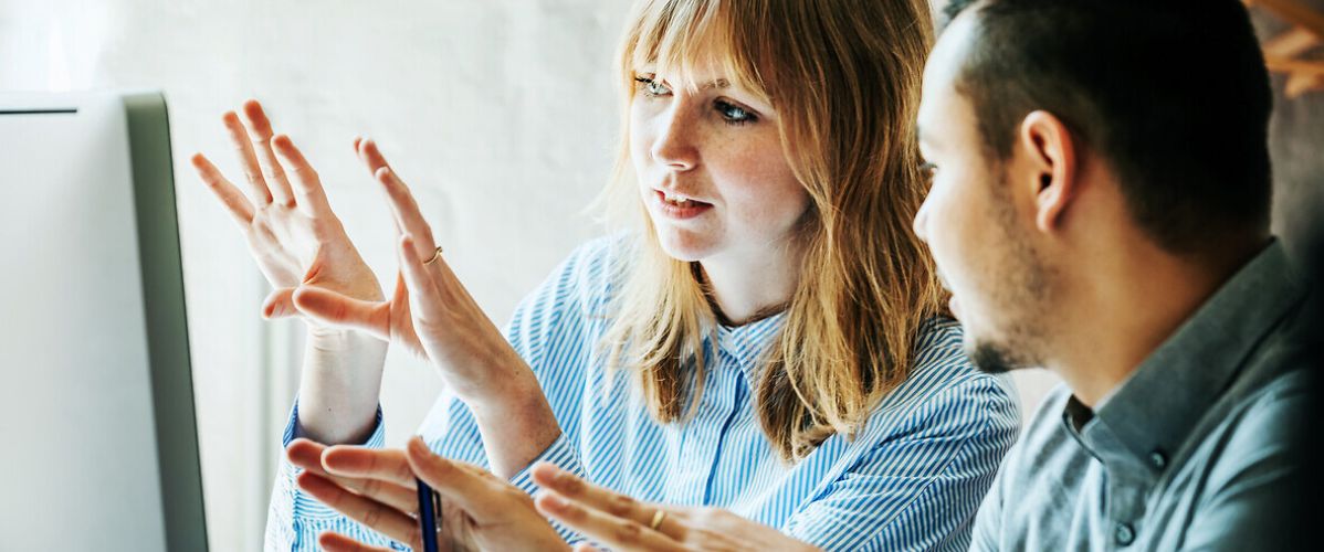 Deux professionnels analysent ensemble un écran dans un bureau lumineux, illustrant la supervision humaine et la coordination dans un projet technologique.
