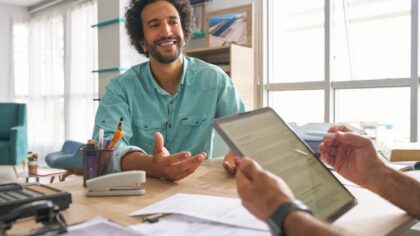 Un homme passant un entretien d'embauche dans un bureau design, avec un recruteur tenant une tablette.